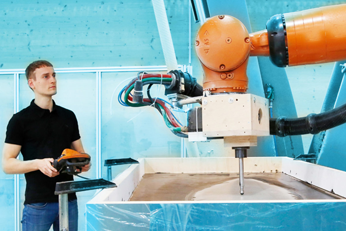 Handwerker arbeitet mit einem Gerät mit Roboterarm. 