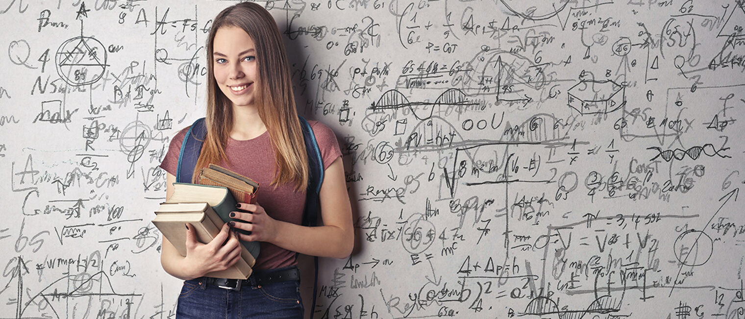 Junge Frau vor Tafel mit Formeln.