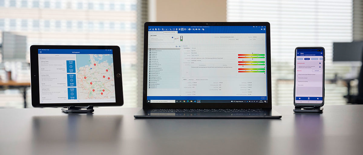 Auf einem Tisch stehen drei verschiedene Endgeräte (Laptop, Tablet und Handy) mit einer ERP-Software