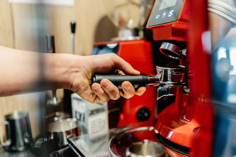 Eine Hand am Griff an einer Gastro-Kaffeemaschine