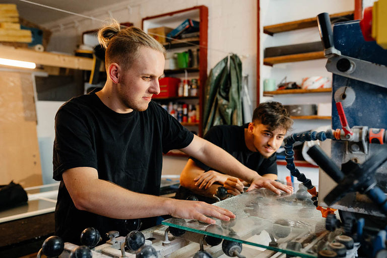 Zwei Glaser-Azubis an der Fräsmaschine in der Werkstatt