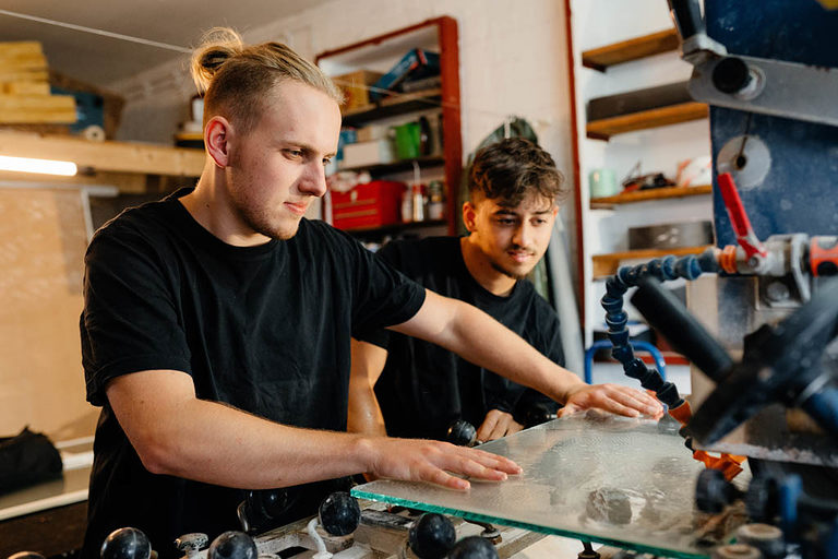 Zwei Glaser-Azubis an der Fräsmaschine in der Werkstatt