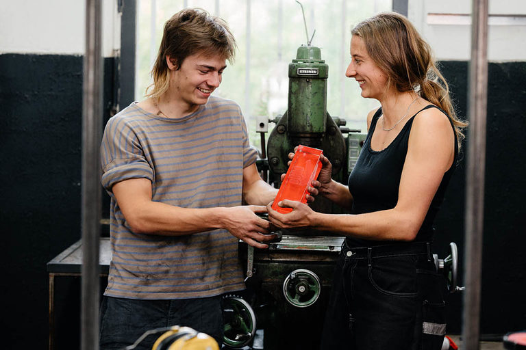 Ein Auszubildender und eine Auszubildende in einer Metallwerkstatt