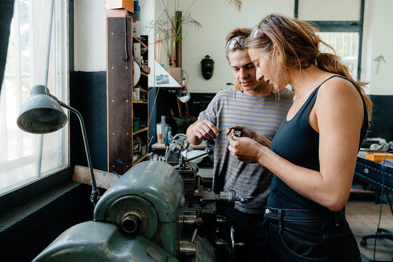 Eine Auszubildende und ein Auszubildender beim Arbeiten in einer Metallwerkstatt