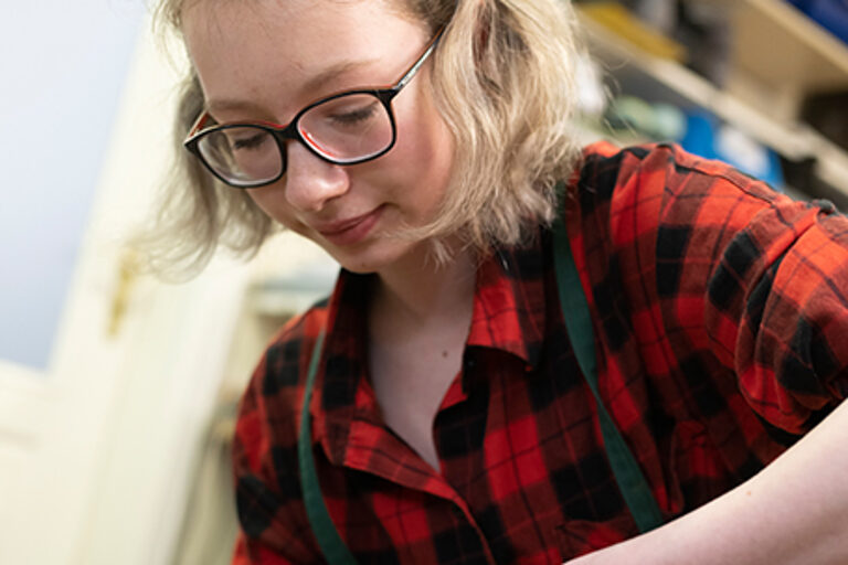 Eine Auszubildende mit einer Schusterzange beim Arbeiten an einem Leisten in einer orthopädischen Werkstatt.