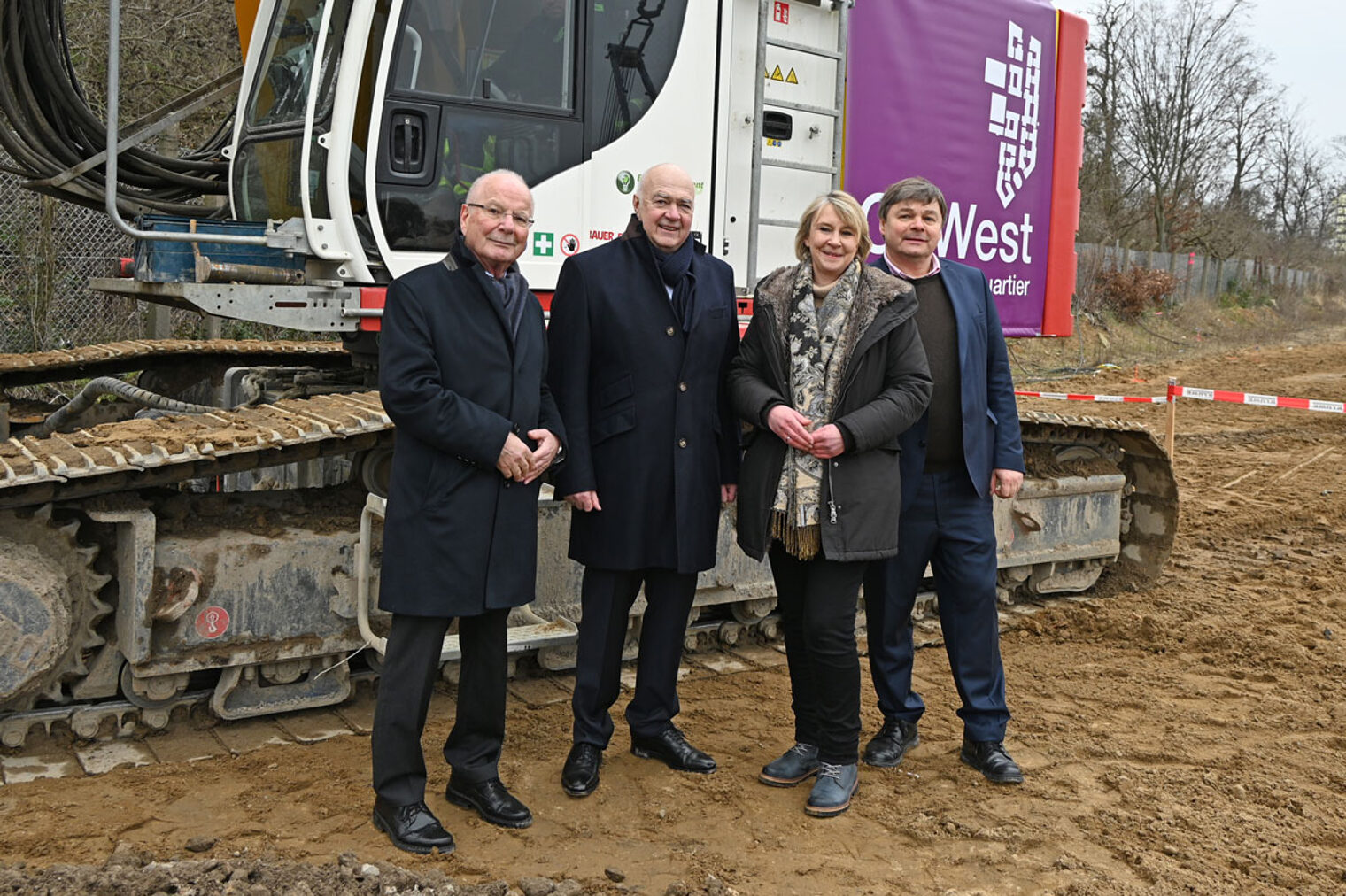 Wohnkompanie-Chef Stephan Allner (rechts), Kurt Zech von der Zech Group (2. v. l.) und Handwerkskammerpräsidentin Carola Zarth beim Baustart des ¿Go West¿-Projekts vor einer Planierraupe.