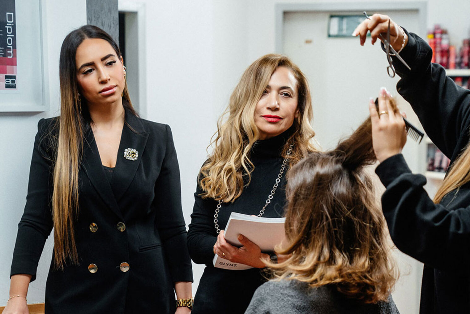 Nurten Tosun (l.) und ihre Tochter Nagihan Tosun (r.) sind darauf bedacht, dass die Friseur-Meisterprüfungen professionell ablaufen und eine gute Qualität haben. Das Bild zeigt sie während einer Prüfungssituation in ihrem Friseurstudio. 