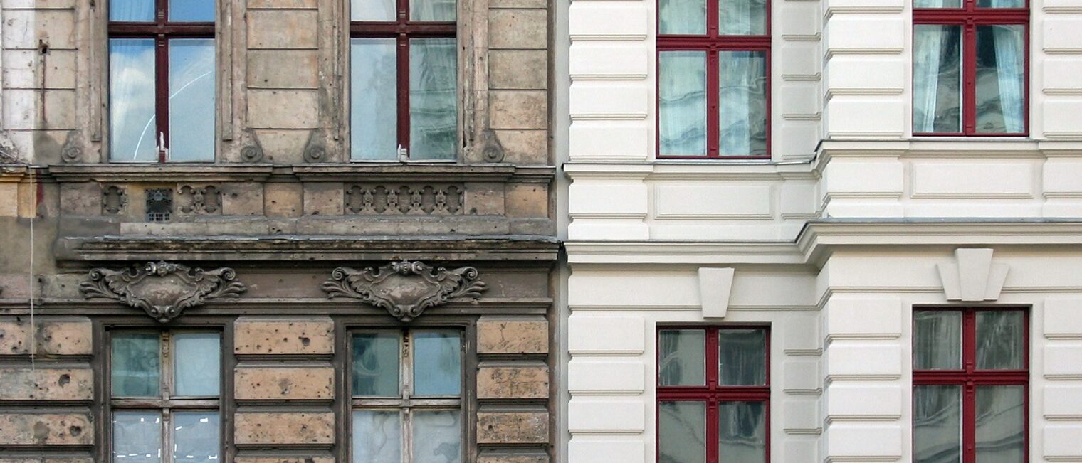Fassade in Berlin zeigt auf der linken Seite eine unsanierte Fassade, auf der rechten Seite eine Fassade mit sanierten Holzfenstern und neuem hellem Anstrich.