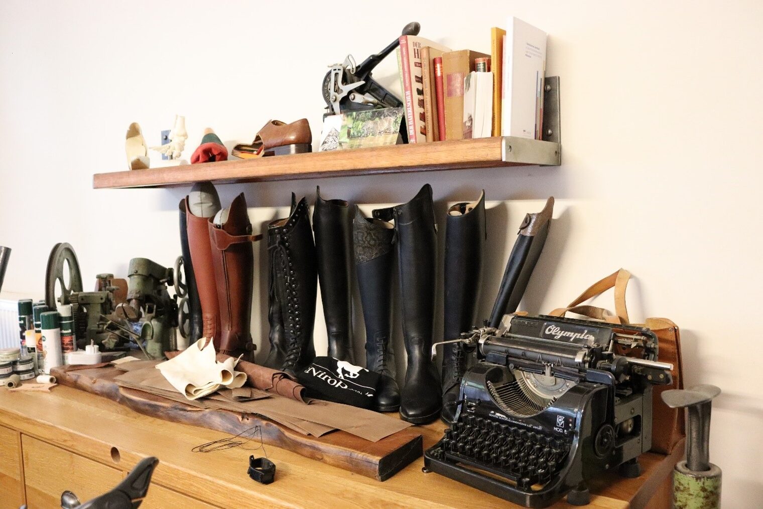 Eindrücke aus einer Werkstatt eines Orthopädieschumachers mit einer Werkbank und Stiefeln sowie einer alten Schreibmaschine