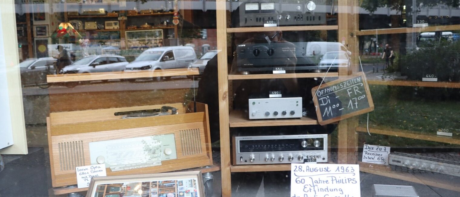Schaufenster des Ladengesch&auml;fts von Peters Werkstatt mit &Ouml;ffnungszeiten und altem Radio