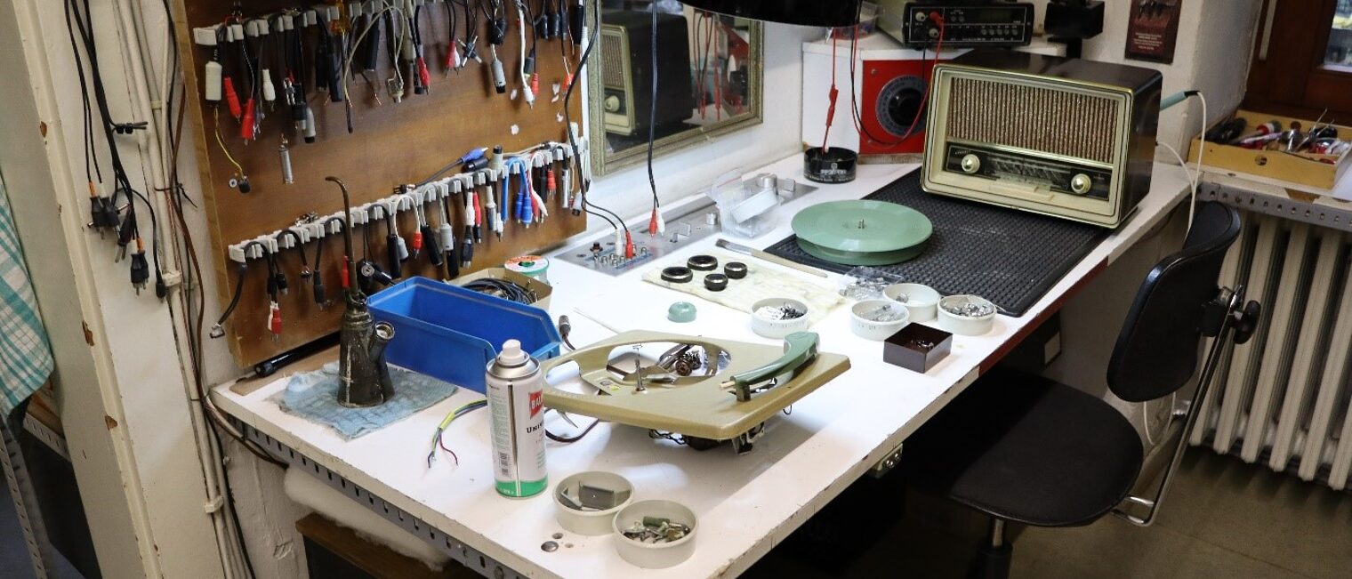 Werkbank von Peters Werkstatt mit Werkzeug und einem alten Radio zur Reparatur im Hintergrund