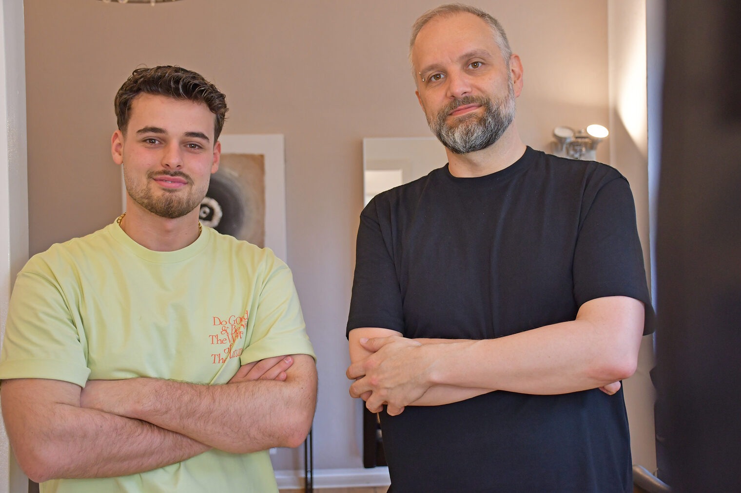 Rigers Bici und Georg Elfinger stehen in einem Friseursalon und lächeln in die Kamera