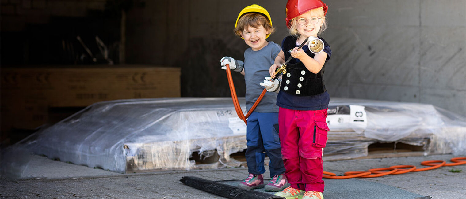 Titelbild des Kita-Wettbewerbs des Handwerks "Kleine Hände, große Zukunft" mit zwei Kindern bei einem Betriebsbesuch. Der Kita-Wettbewerb bringt Kinder und Handwerksbetriebe zusammen.