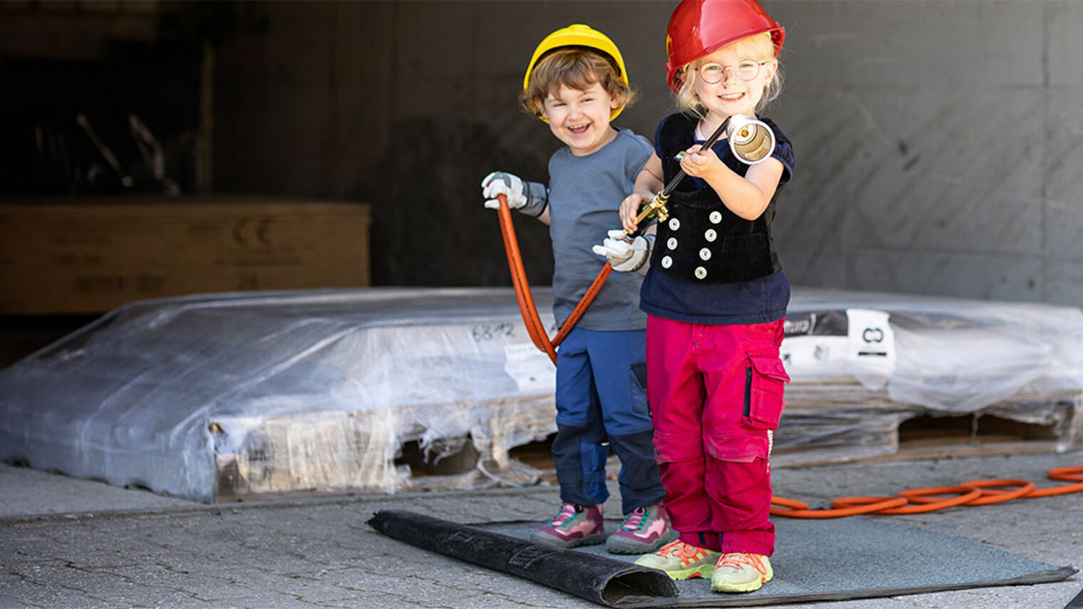 Titelbild des Kita-Wettbewerbs des Handwerks "Kleine Hände, große Zukunft" mit zwei Kindern bei einem Betriebsbesuch. Der Kita-Wettbewerb bringt Kinder und Handwerksbetriebe zusammen.