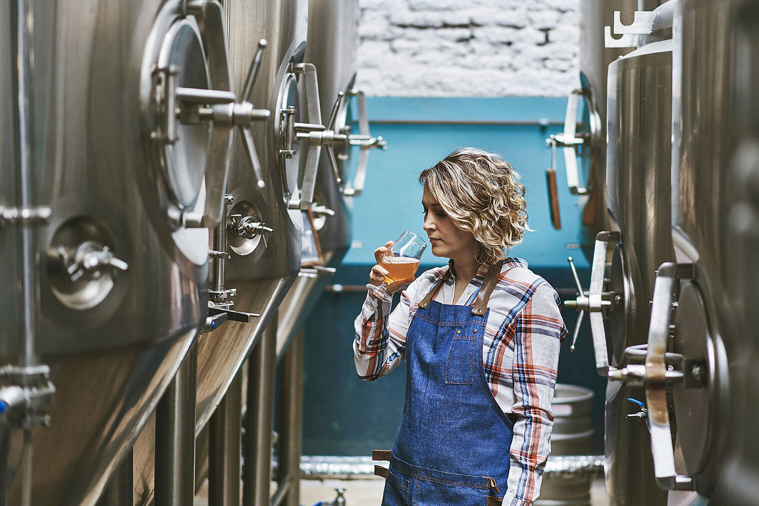 Eine Brauerin riecht an einem selbst gebrauten Bier in einer Brauerei.