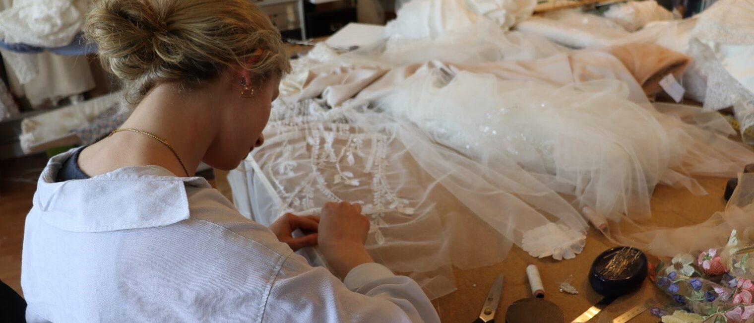 Ladengesch&auml;ft mit Brautkleidern im Atelier Fiebelkorn. Die Azubine von Frau Fiebelkorn arbeitet an einem Kleid. 