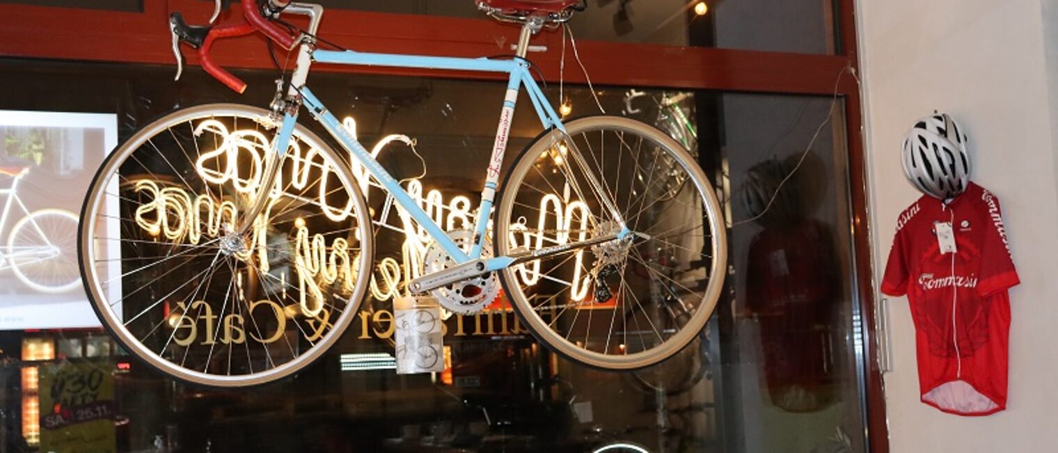 Im Schaufenster des Radkunst Caf&egrave;s ist ein blaues Fahrrad zu sehen. 