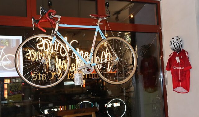 Im Schaufenster des Radkunst Cafès ist ein blaues Fahrrad zu sehen. 