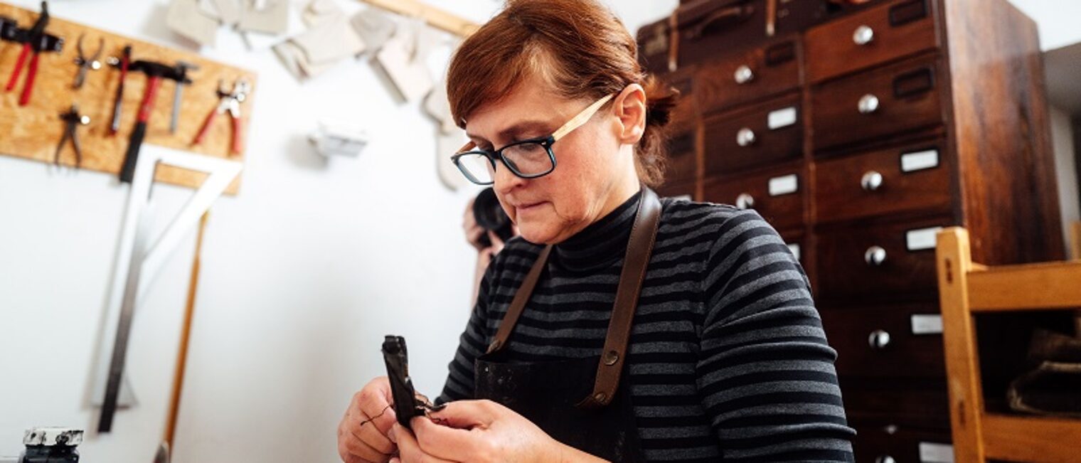 Die Werkstattleiterin in der Unikat Taschenmanufaktur repariert ein Lederst&uuml;ck. 