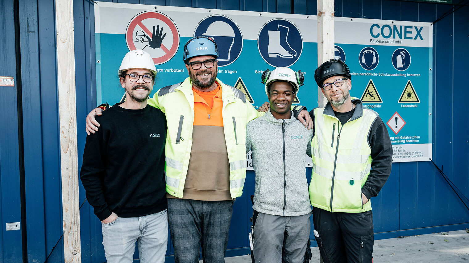 Vier Stahlbetonbauer posieren lächelnd vor der Kamera