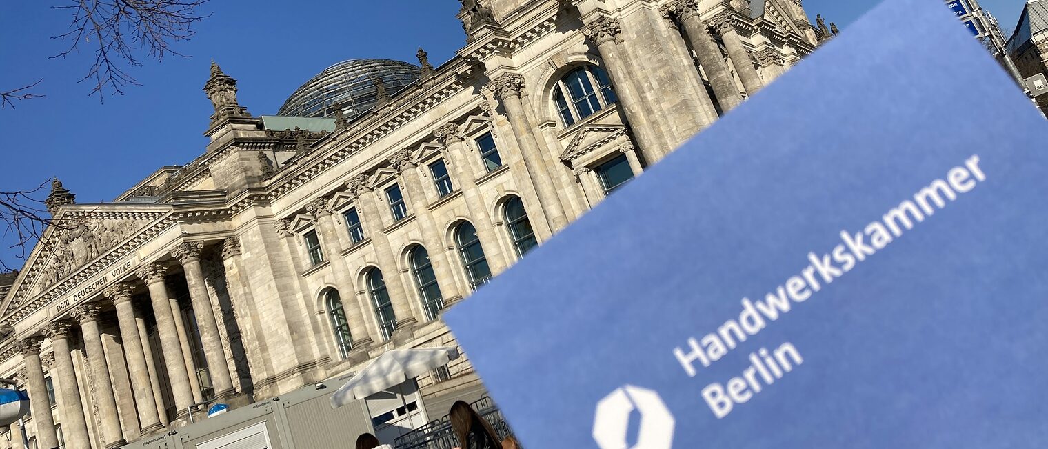 Das Gebäude des Bundestags und ein Logo der Handwerkskammer Berlin