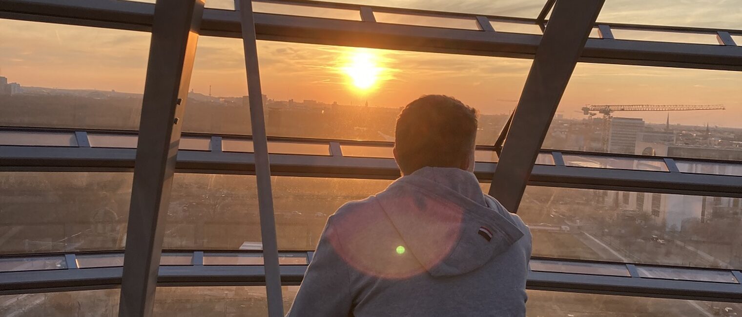 Schulterblick: ein Azubi beobachtet den Sonnenuntergang aus der Glaskuppel des Bundestags