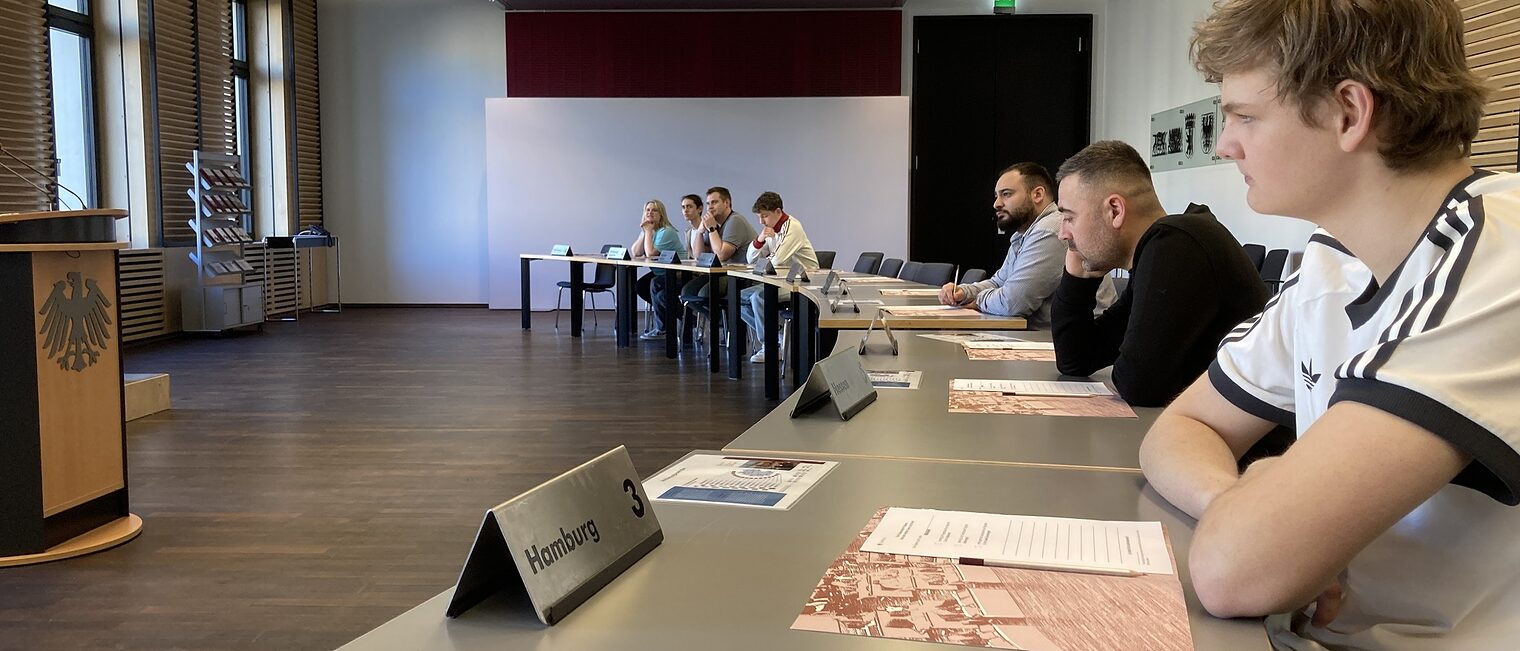 Azubis zu Besuch im Bundesrat: mehrere Azubis sitzen an einem langen Tisch und hören zu.
