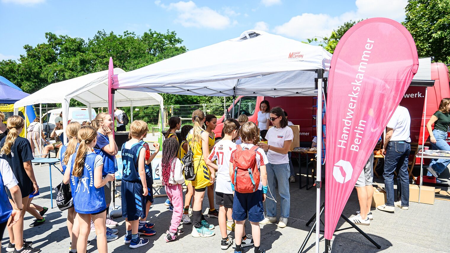 Schulkinder beim Finale der ALBA Grundschulliga 2025 in der Max-Schmeling-Halle vor dem Zelt der Handwerkskammer Berlin