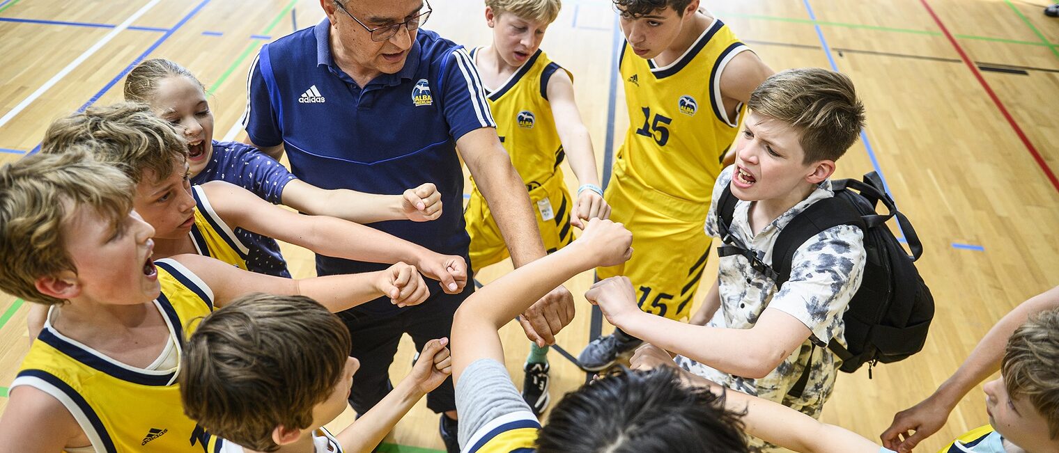 Ein Schulkinder-Team mit dem Schiedsrichter beim Basketball-Finale der ALBA Grundschulliga 2025 in der Max-Schmeling-Halle