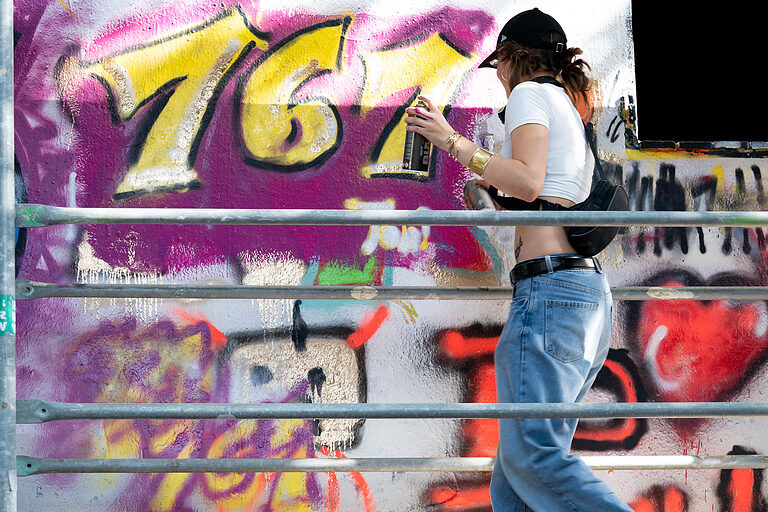 Eine junge Frau mit der Sprühdose an der bunt bemalten Mauer am Tag des Handwerks am 20. September 2025 im Mellowpark Berlin