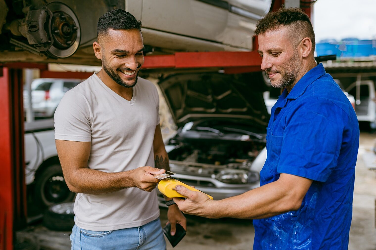Mechaniker nimmt kontaktlose Zahlung in Autowerkstatt entgegen