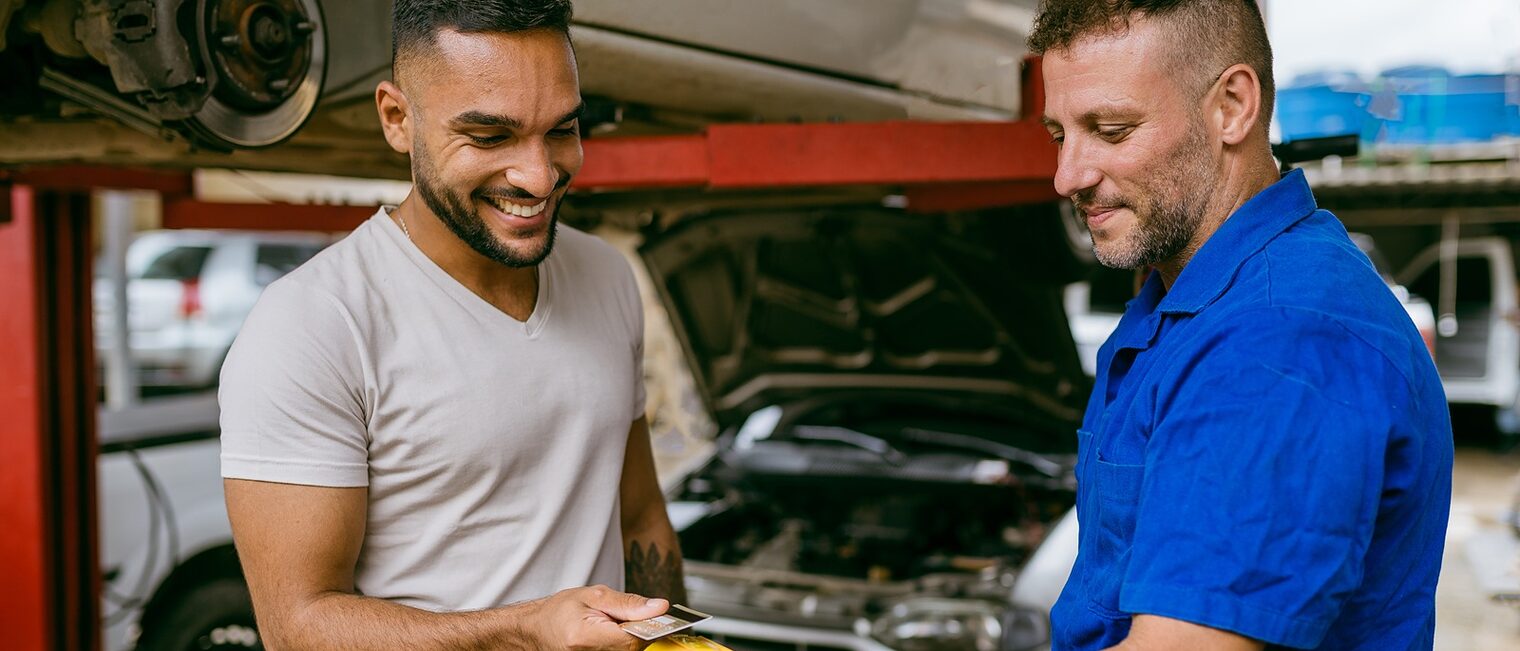Mechaniker nimmt kontaktlose Zahlung in Autowerkstatt entgegen