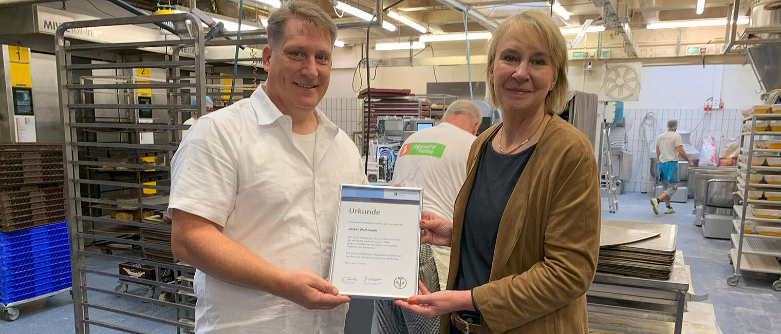 Carola Zarth überreicht Tobias Menge, Betriebsleiter der Bäckerei Walf GmbH, die Ehrenurkunde.