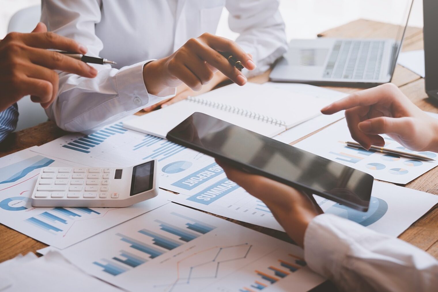 Hände am Tisch: Businessplan, Rechner, IPad