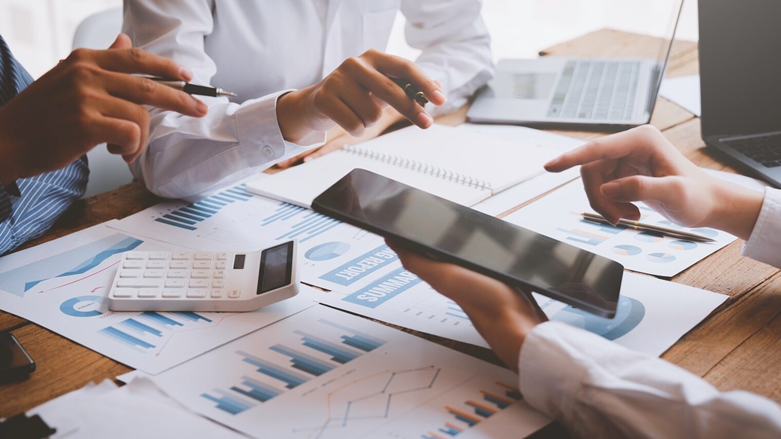Hände am Tisch: Businessplan, Rechner, IPad