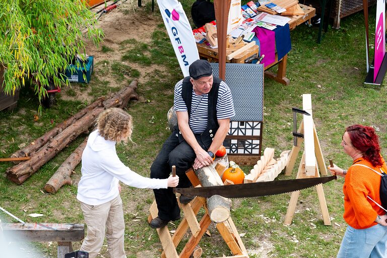 Zwei junge Frauen sägen an einem Stück Holz an einem Aktionstisch am Tag der Handwerks 2026 im Mellowpark