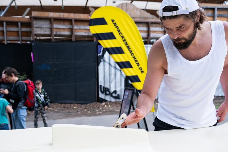 Ein junger Mann mit seinem Fingerboard an der Rampe am Tag des Handwerks 2062 im Mellowpark Berlin.