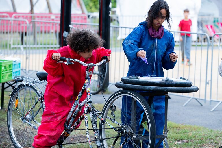 Zwei Mädchen in bunter Schutzkleidung mit Farbtuben am Tag der Handwerks 2026 im Mellowpark Berlin.