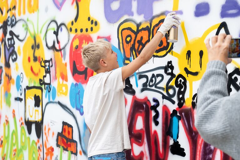 Bild von hinten: ein Junge besprüht eine Graffiti-Wand am Tag der Handwerks 2026 im Mellowpark Berlin.