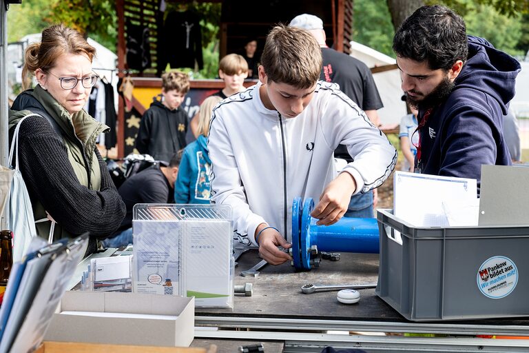 Zwei Jungen beim Werkeln an einem blauen Rohr an einem Aktionsstand am Tag der Handwerks 2026 im Mellowpark Berlin.