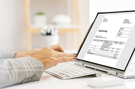 Hand an einer E-Rechnung am Laptop